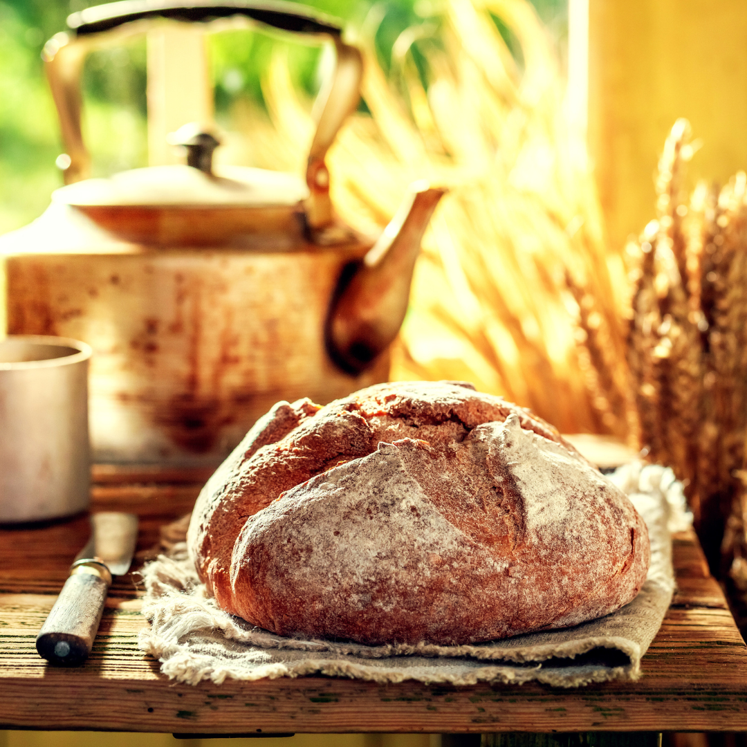 Tisch mit Ähren, Messer, Brot, Tuch und Kanne